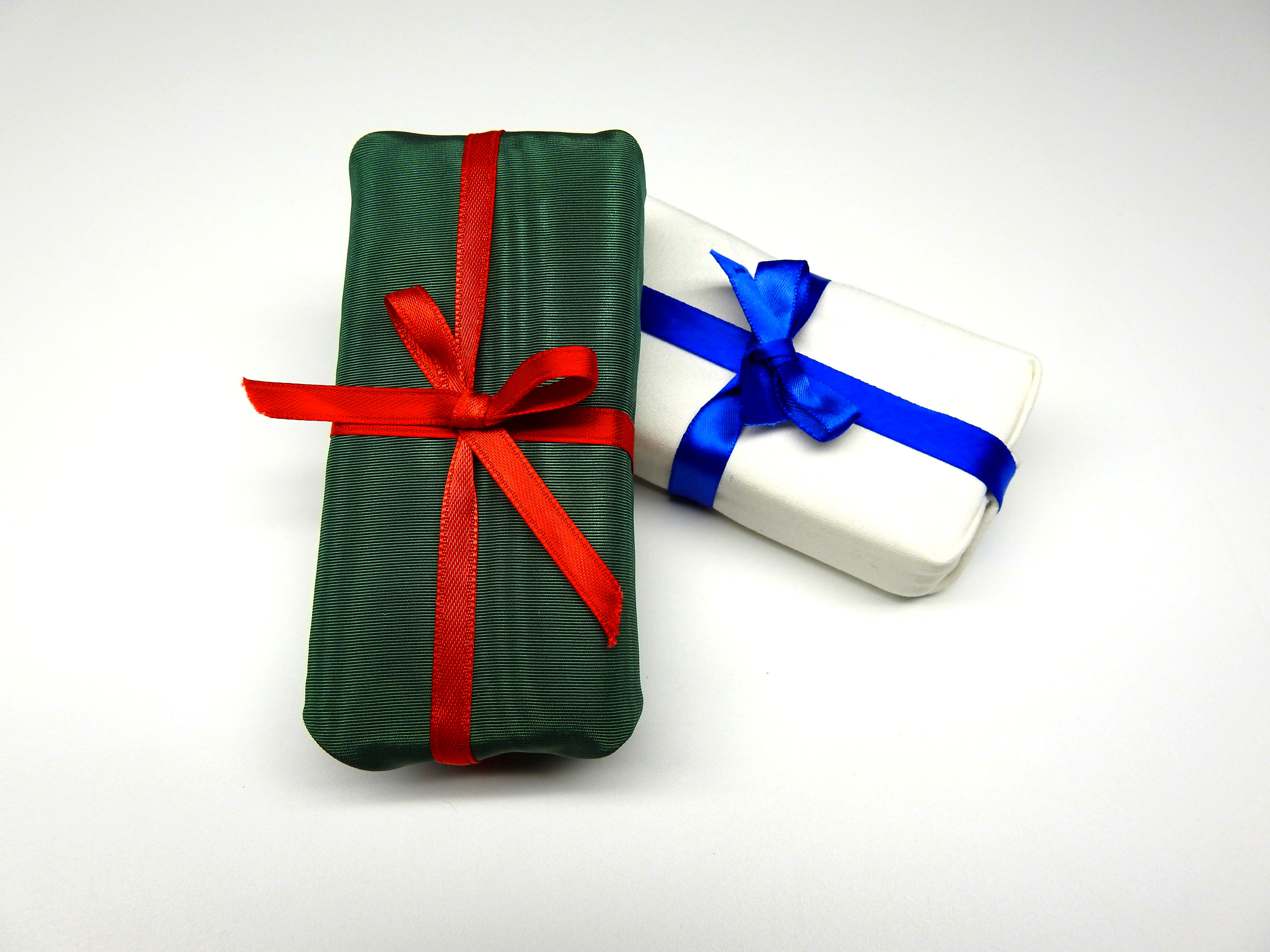 Finished gift box shaped pin cushions. One is white with a blue ribbon (winter,) the other is green with a red ribbon (joyful.)